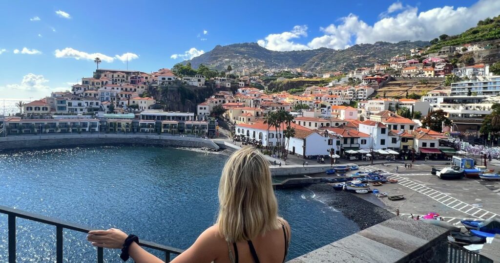 Girl looks at the view of Camara de Lobos, a traditional Madeiran fishing village with a harbour and small beach.