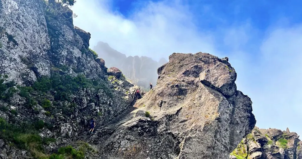 Hikers wave from a large boulder on the Pico Grande hike in Madeira.