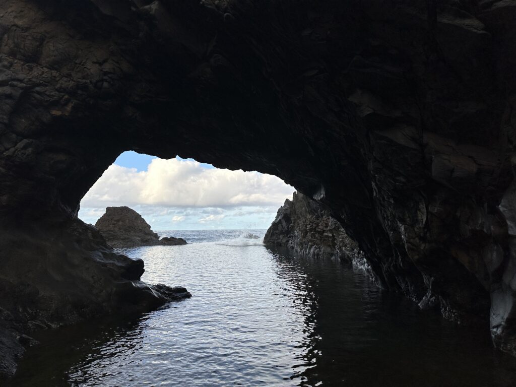 View of the ocean through a volcanic archway in Seixal, Madeira.