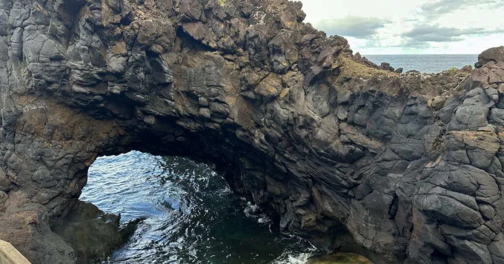 Sculpted volcanic rock forms an archway over a natural pool in Seixal, Madeira.