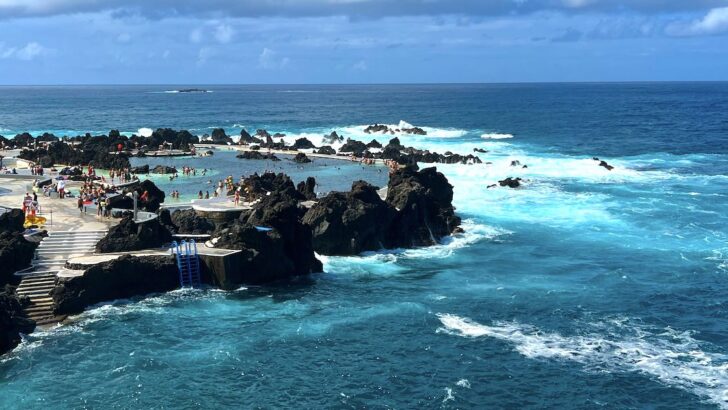 Waves roll in next to the busy Porto Moniz Natural Pools in Madeira.