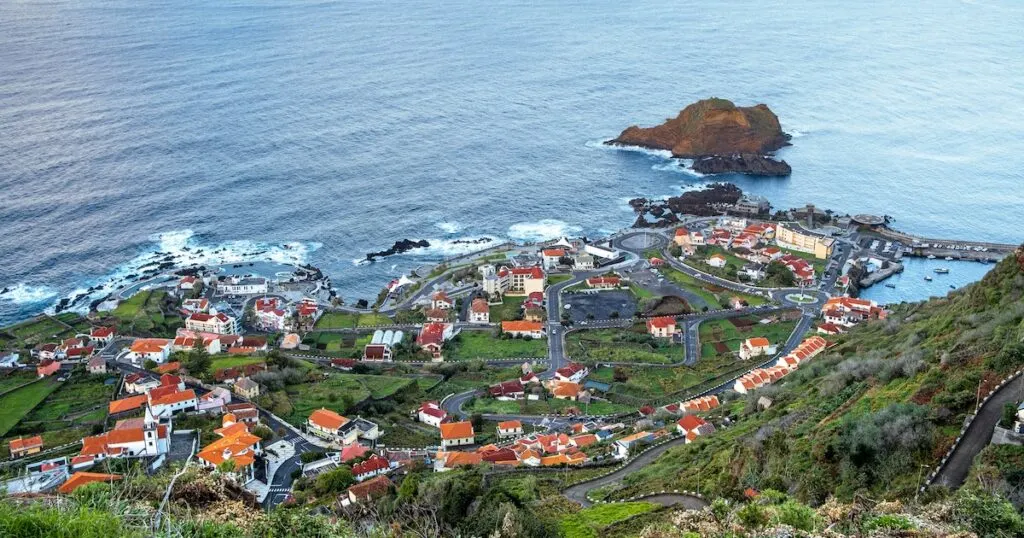 Viewpoint over Porto Moniz shows volcanic lava pools and Madeiran houses surrounded by farm terraces.