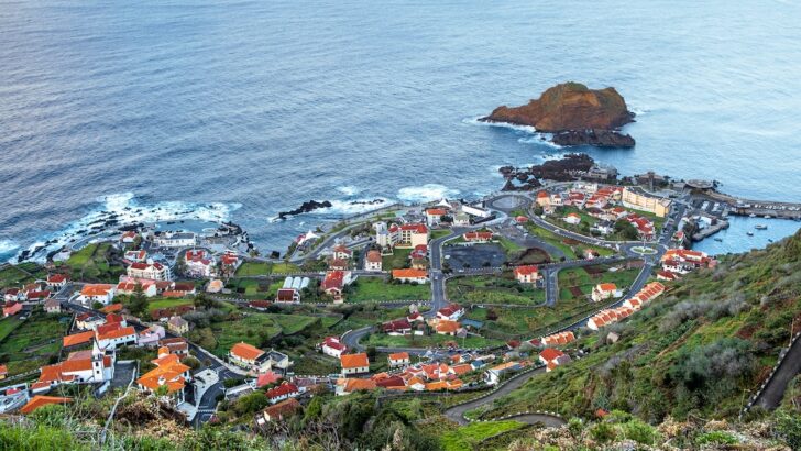 Viewpoint over Porto Moniz shows volcanic lava pools and Madeiran houses surrounded by farm terraces.