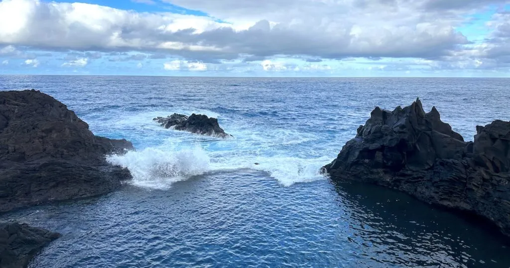 A wave crashes over the edge of the lava pools in Seixal.