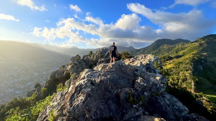 A man stands on a boulder at the summit of Pico Facho in Machico.